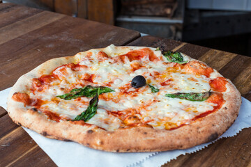Pizza Margherita freshly baked on dark rustic wood background