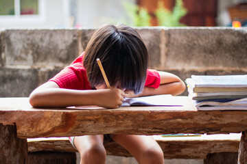 A girl sitting on a wooder table doing homework