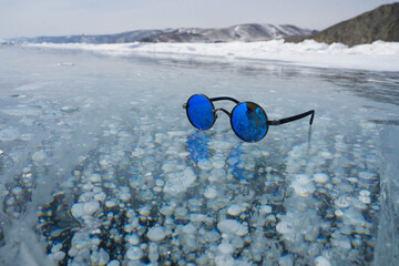 blue sunglasses lie on transparent ice
