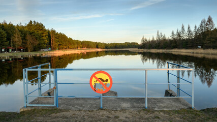 Zalew na Podlasiu w Polsce ze znakiem zakazu pływania umieszczonym na tamie - obrazy, fototapety, plakaty