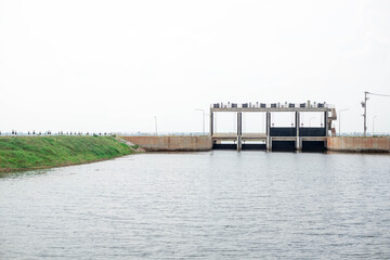 Obraz premium Cement floodgate in earth dam for torrential rains making river overflow,
