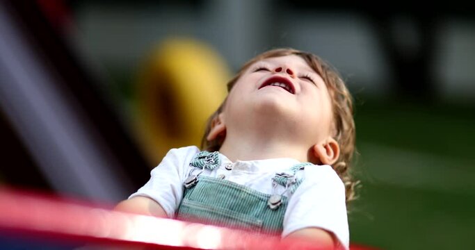 Carefree little boy spinning at playground carousel close-up face smiling