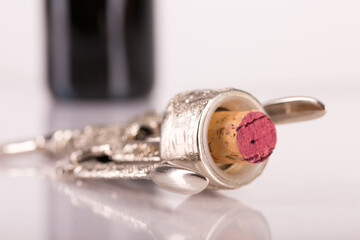 Red wine bottle, cork stopper and an italian prestigious corkscrew on a white background