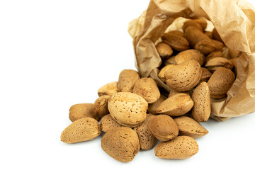 bunch of shelled almonds going out of a recycled kraft paper bag with a white background. Concept of bulk selling and ecological