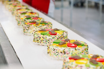 Decorating cakes on the conveyor of a confectionery factory.