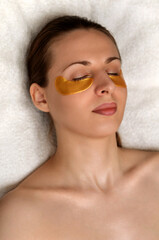 Golden flakes with collagen. Cosmetic procedure, the woman's face with gold patches under the eyes