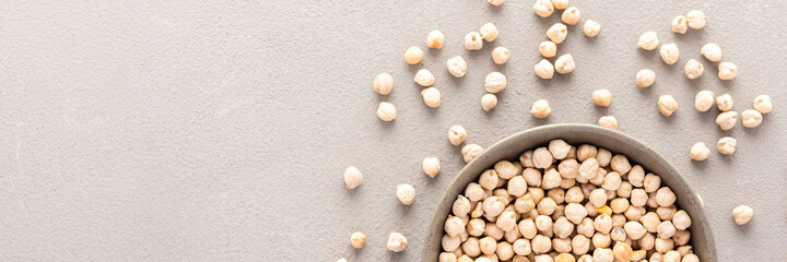 Legumes in bowl and scattered in the background, chickpeas in a plate banner, top view, copy space