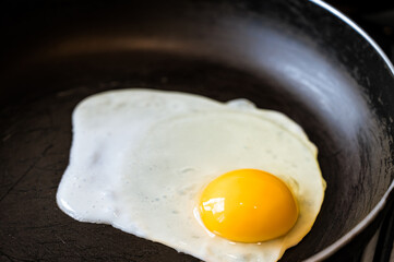 The egg is fried in a frying pan without oil. Healthy breakfast. Close-up.