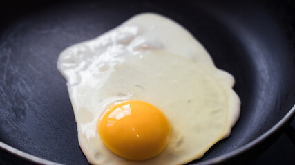 The egg is fried in a frying pan without oil. Healthy breakfast. Close-up.