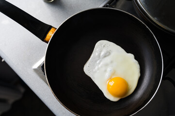 The egg is fried in a frying pan without oil. Healthy breakfast. Close-up. View from above.
