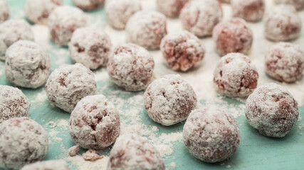 Meat balls covered with flour lie on the surface. The cooking process. Tasty food. Close-up.