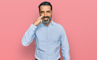 Obraz premium Middle aged man with beard wearing business shirt pointing with hand finger to face and nose, smiling cheerful. beauty concept
