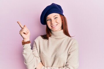 Young red head girl wearing french look with beret smiling happy pointing with hand and finger to the side