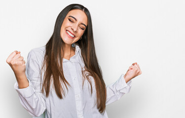 Young beautiful woman wearing casual white shirt very happy and excited doing winner gesture with arms raised, smiling and screaming for success. celebration concept.