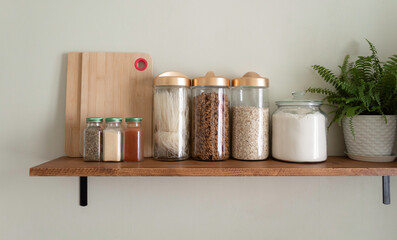 Zero waste storage in the kitchen. Various cereals, pasta, oatmeal, flour in reusable glass jars on the table on the wooden shelf. Eco friendly lifestyle