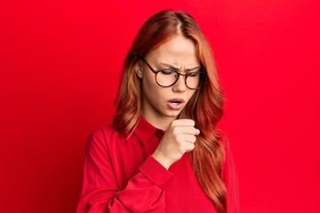 Young beautiful redhead woman wearing casual clothes and glasses over red background feeling unwell and coughing as symptom for cold or bronchitis. health care concept.