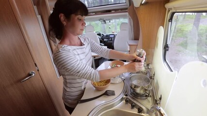 Woman cooking in camper, motorhome interior