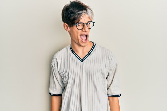 Young hispanic man wearing casual clothes and glasses winking looking at the camera with sexy expression, cheerful and happy face.