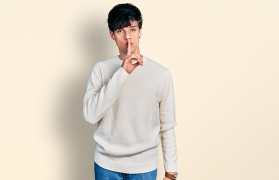 Handsome hipster young man wearing casual winter sweater asking to be quiet with finger on lips. silence and secret concept.