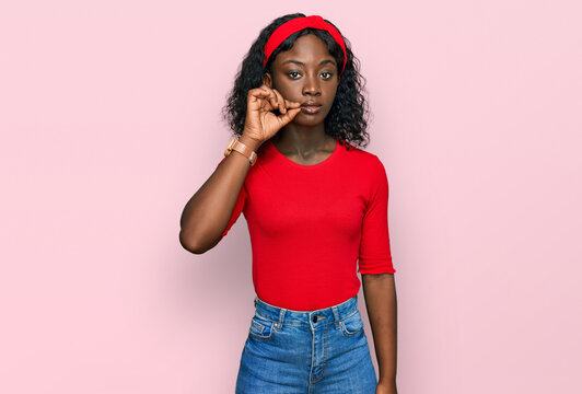 Beautiful african young woman wearing casual clothes mouth and lips shut as zip with fingers. secret and silent, taboo talking