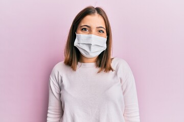 Young beautiful woman wearing medical mask with a happy and cool smile on face. lucky person.