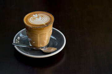 cup of hot latte art coffee on wood table in morning sun light, relax time
