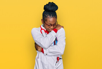 Young african american woman wearing doctor uniform and stethoscope hugging oneself happy and...