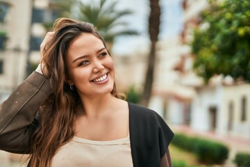 Obraz premium Young hispanic woman smiling happy standing at the city.