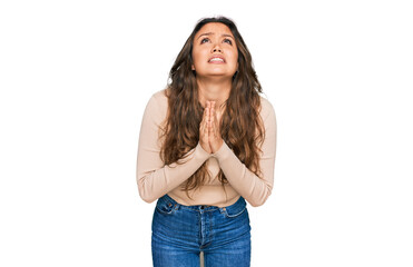 Young hispanic girl wearing casual clothes begging and praying with hands together with hope expression on face very emotional and worried. begging.