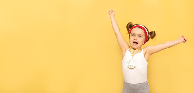 Sport Success And Win Children - Happy Athlete Champion Child Girl Celebrates First Place Victory Gold Medal.Sport Kid Posing Isolated Over Yellow Studio Background With Medal. Banner,mock,copy Space