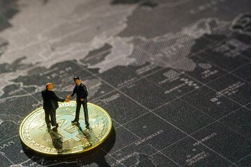 Miniature businessman handshake success deal business on Gold bitcoin and map background