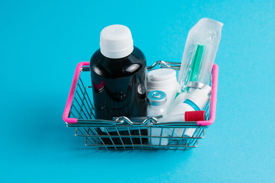 Medicines In A Shopping Cart For A Shopper From A Supermarket On A Blue Paper Background. The Concept Of Medicine And The Cost Of Treatment.