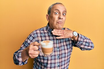 Handsome senior man with grey hair drinking a cup coffee cutting throat with hand as knife, threaten aggression with furious violence