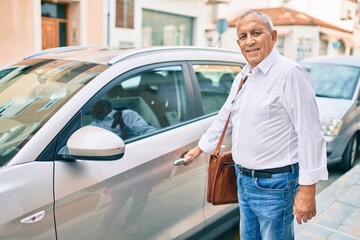 Senior man smiling happy opening car at the city.