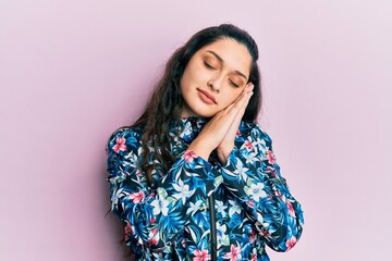 Beautiful middle eastern woman wearing casual floral jacket sleeping tired dreaming and posing with hands together while smiling with closed eyes.