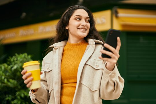 Young middle east woman using smartphone drinking coffee at the city.