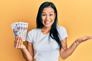 Beautiful hispanic woman holding 500 russian ruble banknotes celebrating achievement with happy smile and winner expression with raised hand