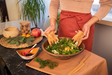 girl making salad with wooden forks in the kitchen