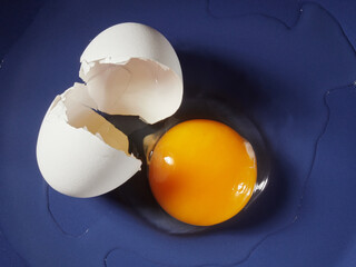 Egg on a black background. Broken chicken egg. The yolk spilled onto the table