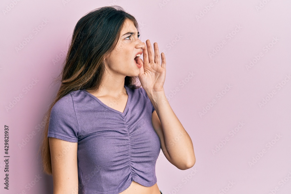 Poster young caucasian woman wearing casual clothes shouting and screaming loud to side with hand on mouth.