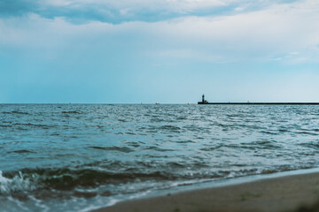 Fototapeta na wymiar Sea waves at Odessa beach with lighthouse on background