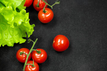 Fresh lettuce and cherry tomatoes on a dark background.