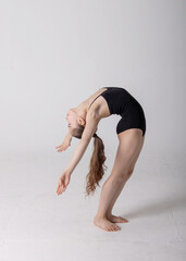 preteen girl gymnast trains on white background in black leotard. children's professional sports....