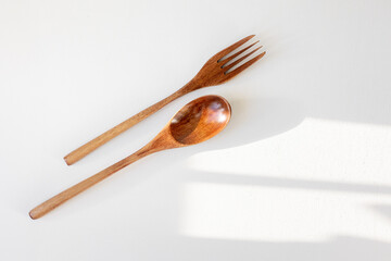 wooden fork spoon on a white background, eco-friendly cutlery without harm to the planet, conscious consumption. wood in the interior of the house and in the kitchen. wooden spoon and fork in a woman