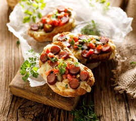 Bruschetta with cheese and sausage sprinkled with herbs, close up view