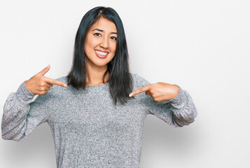 Beautiful asian young woman wearing casual clothes looking confident with smile on face, pointing...