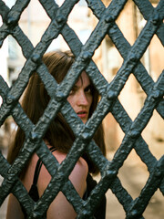 The woman looks into the camera near the ancient gate. Modern portrait of a young woman.