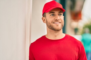 Young caucasian deliveryman smiling happy standing at the city.