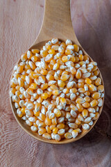 Corn seeds in a wooden spoon on wooden background.