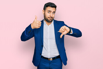 Young hispanic man wearing business jacket doing thumbs up and down, disagreement and agreement...